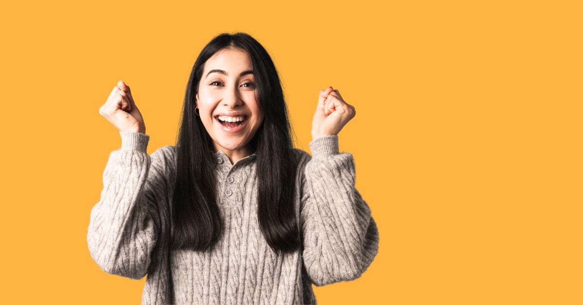 A happy delighted women cheering with her arms raised.